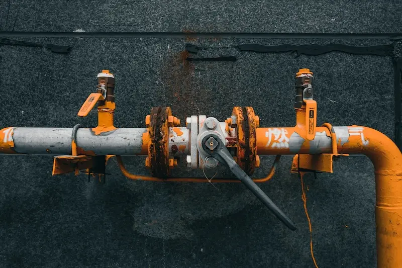 Nahaufnahme eines alten, verrosteten orangen Absperrventils an Industrierohren